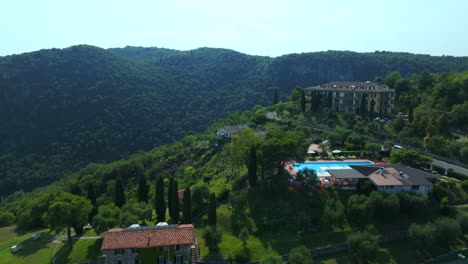 Luftflug-über-Der-Residenz-San-Michele-Mit-Punto-Panoramico-Lago-Im-Hintergrund-Mit-Blick-Auf-Den-Grünen,-Bewaldeten-Hügel