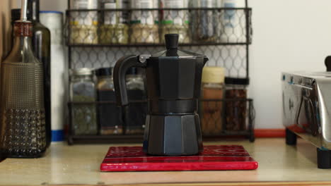 someone places a stovetop espresso maker on kitchen counter