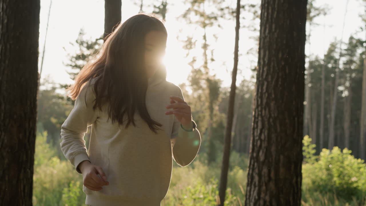 una mujer con el pelo rojo largo corre en el parque al atardecer. una mujer joven realiza ejercicios cardiovasculares corriendo bajo la luz del sol en el aire fresco. rutinaria de entrenamiento por la noche
