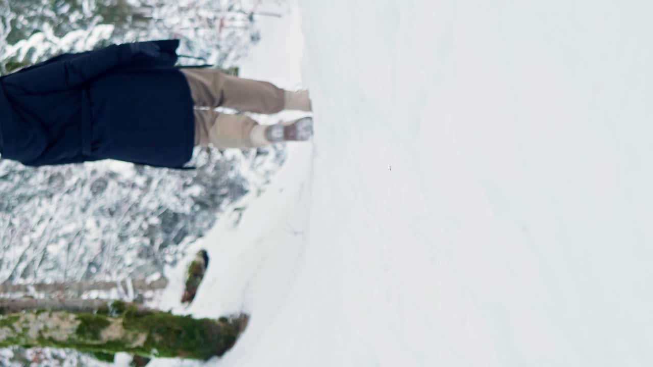Woman walking away from the camera through winter snow wearing boots and winter clothing
