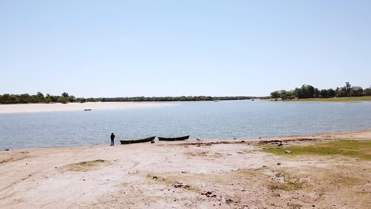 두 대의 카누 옆 강 연안에서 낚시하는 남자의 드론 촬영