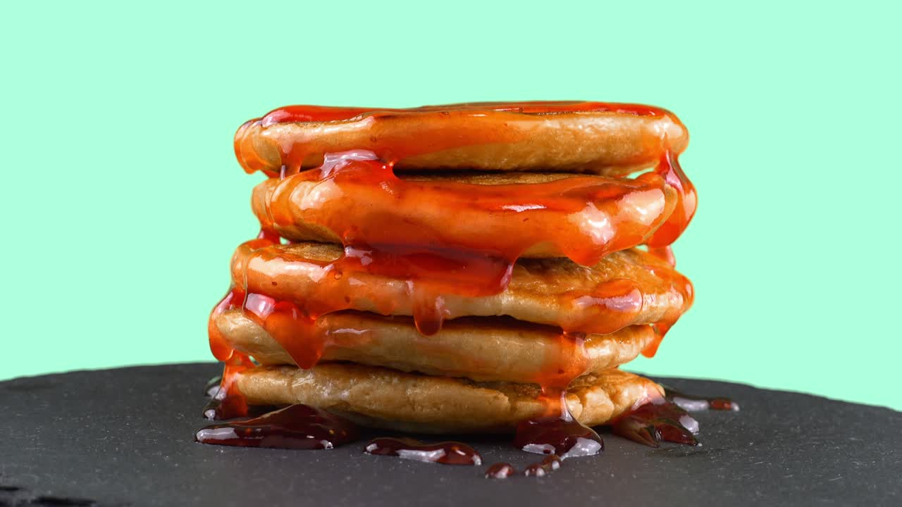 딸기 으로 된 팬케이크: 팬케이크는 검은 슬레이트 둥근 돌 위에 있습니다. 파란색 배경, 아쿠아마린.