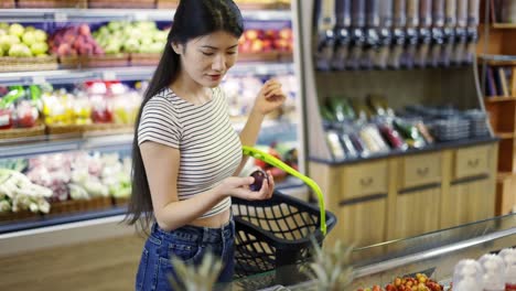 an asian shop visitor chooses fruits and vegetables in special packages. hold a basket in your hands