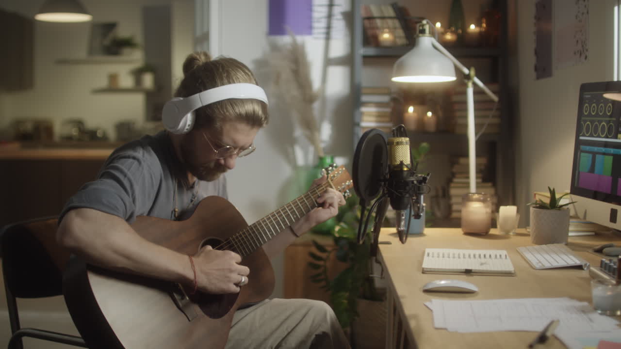Man Playing Guitar and Using Computer in Home Studio
