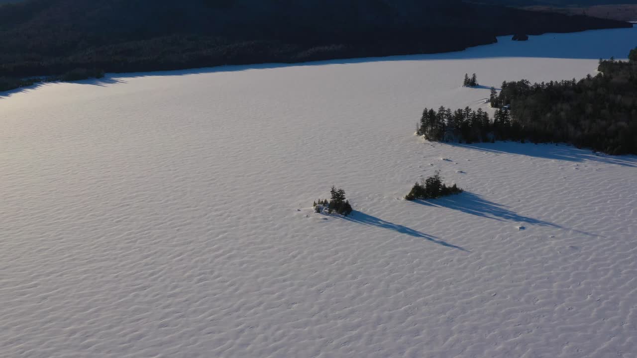 Scivolata aerea che inquadra dall'alto due isole in un lago ghiacciato con lunghe ombre