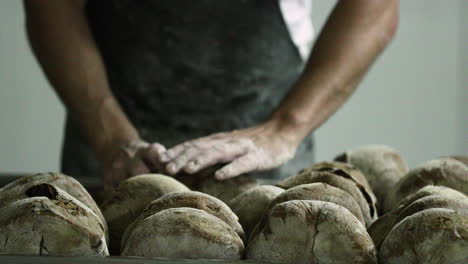 baker arranging the sourdough breads on a baking rack in a bakery