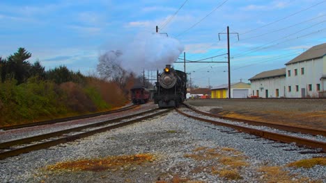 a steam engine moving along a curve with a passenger train just passed