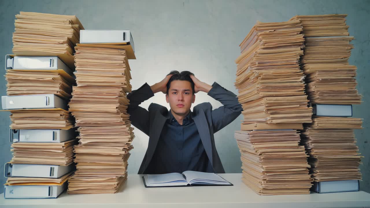 Stressed businessman overwhelmed by paperwork in office