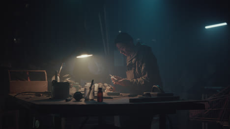 a bombmaker assembles a bomb in his workshop at night