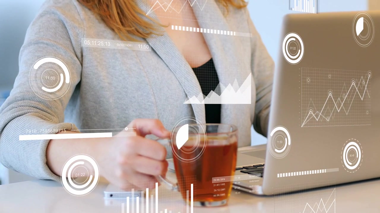 Donna che digita su un laptop attivando grafici HUD, mentre solleva una tazza, sorseggia e poi riprende l'analisi dei dati