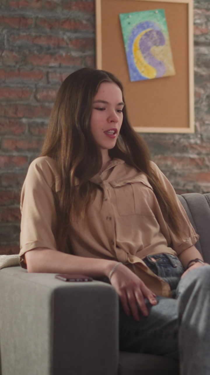 예쁜 젊은 여자와 긴 머리의 남자가 스포츠 경기 방송에서 소파에 함께 앉아 이야기합니다. 축구 팬의 부부는 거실에서 시간을 보내고 있습니다.