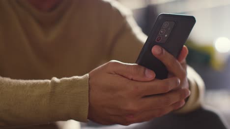 close up of muslim man at home holding mobile phone and scrolling