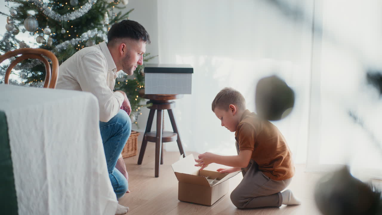 un niño ayuda a su padre a decorar el árbol de navidad saca las bolas de navidad de la caja