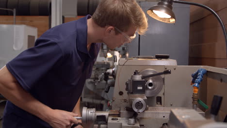 male apprentice in factory using lathe shot in slow motion