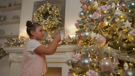 girl decorates christmas tree with balls, lights and ornaments