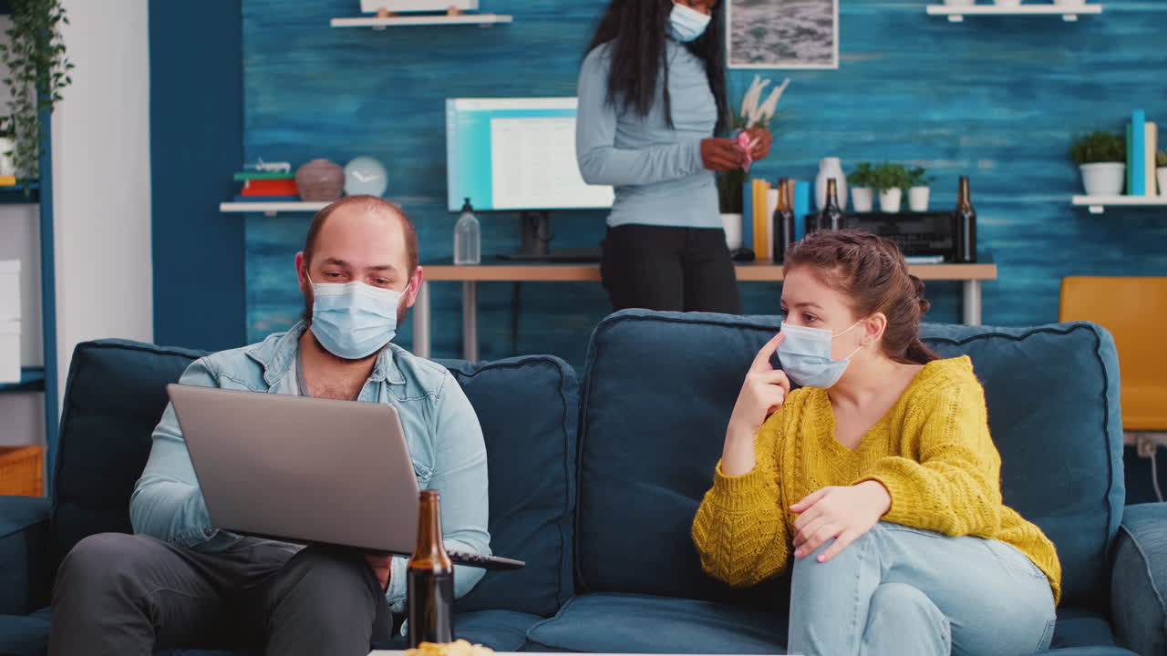 Friends looking at laptop socializing during party sitting on couch