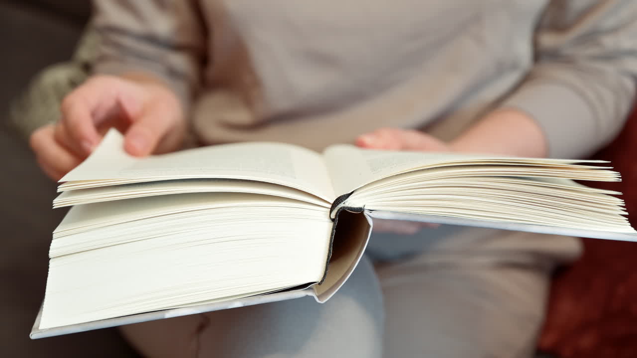 Close up of a woman reading a book at on the couch at home