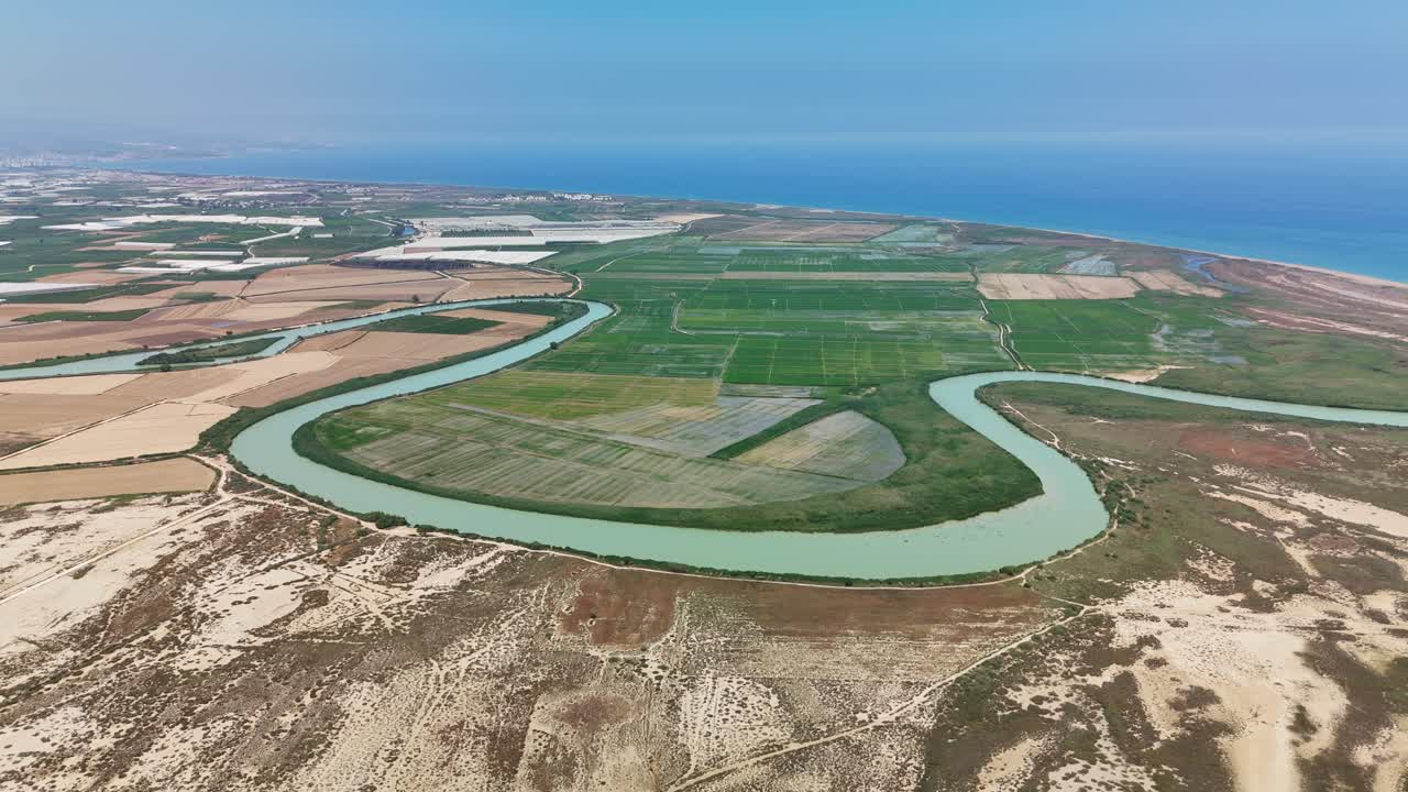 Aerial view of winding river in arid landscape meeting the sea