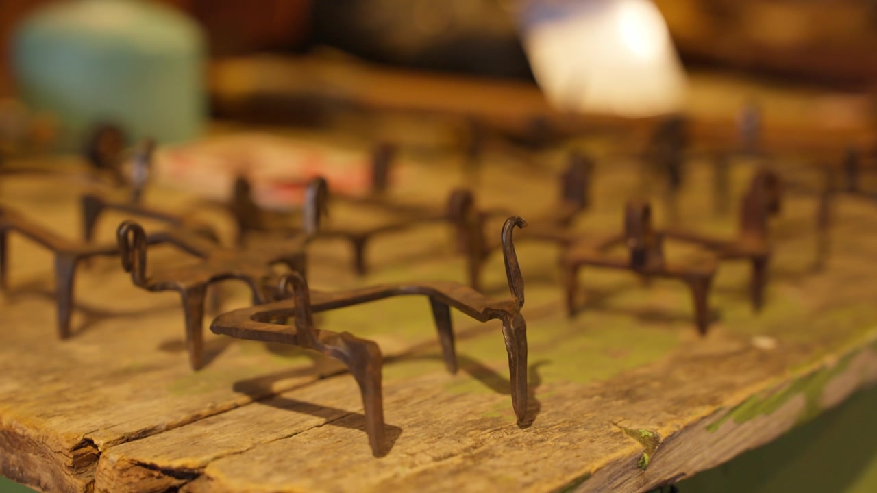 Outils traditionnels de gaucho en fer forgé disposés sur une table en bois rustique dans un décor de ranch patagonien, présentant de l'équipement d'élevage artisanal et un héritage équestre rural, gros plan à main levée