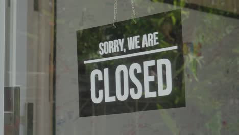 person turns the signboard with the inscription "open" to "closed" sign on a storefront window