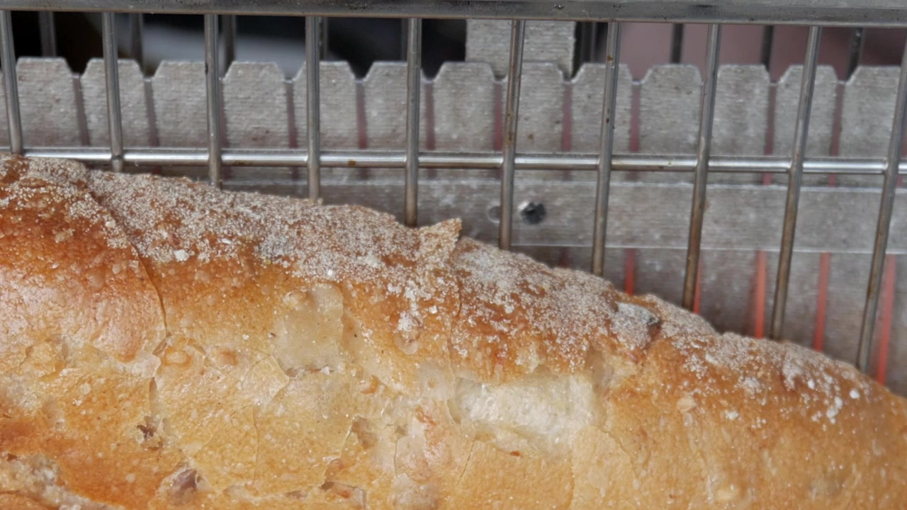 Slice of bread on vertical toaster. Incandescent heating elements glowing orange behind