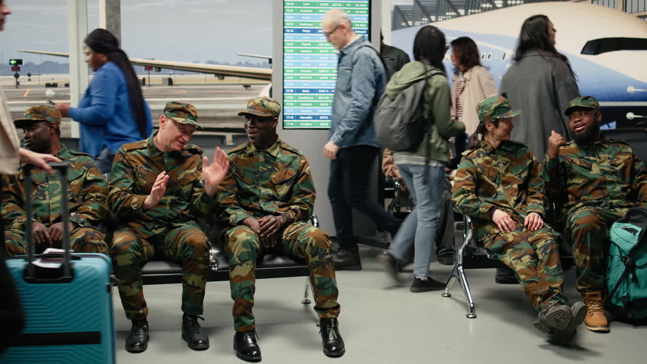 Soldati dell'esercito che chiacchierano e viaggiano, seduti su sedie in aeroporto
