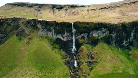 Aerial-Of-Long-Waterfall-From-Rocky-Mountain-During-Summer