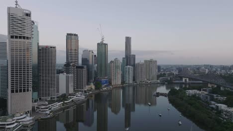 cinematic drone over river towards brisbane city at sunrise