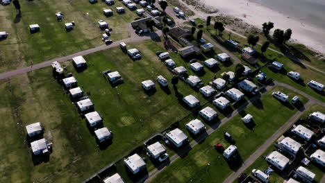 un montón de caravanas bien estacionadas acampando en el campamento campistas disfrutando de vacaciones descanso de vacaciones niños jugando playa de arena aéreo drone pájaros ver olas orilla verano sentirse feliz relajado viaje europeo divertido