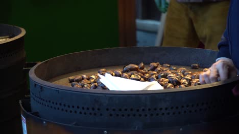 Close-up-of-the-traditional-roasting-of-chestnuts-at-the-Christmas-Village-opposite-Town-Hall-in-Vienna,-Austria