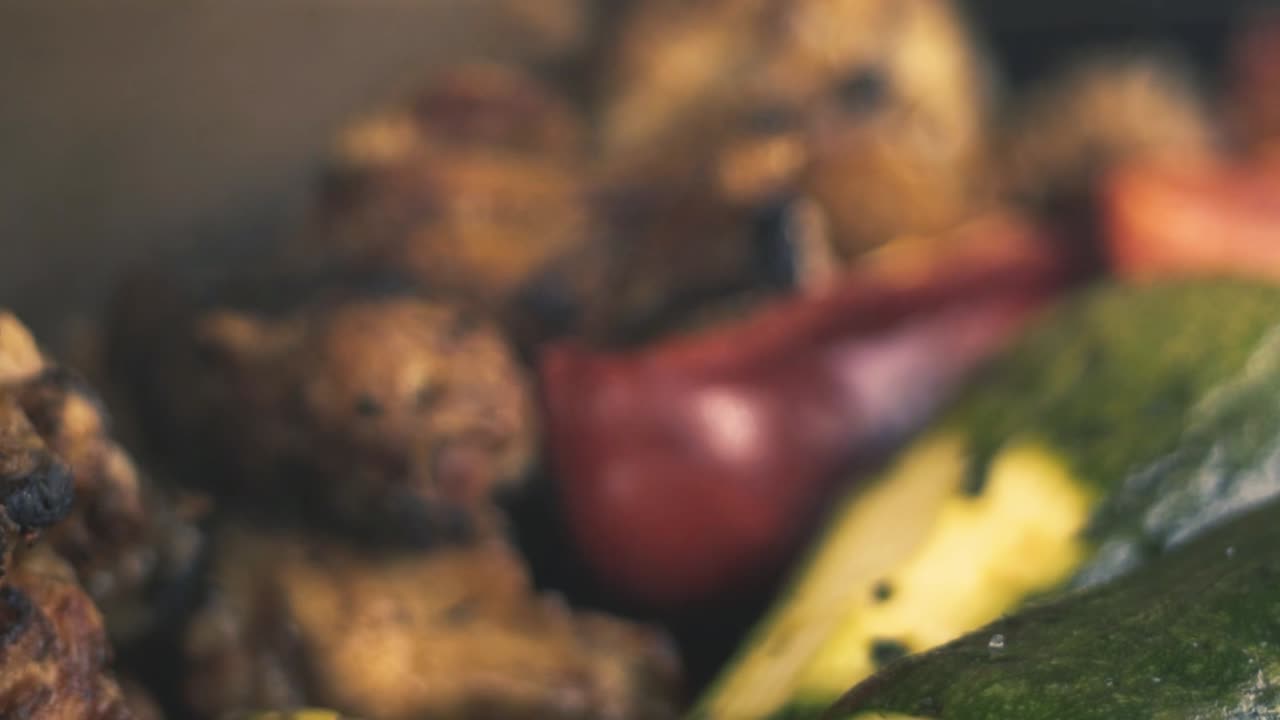 Slow-motion close-up chicken wings and grilled vegetables, (Italian squash and red pepper or red pepper - smoke from the charcoal grill)