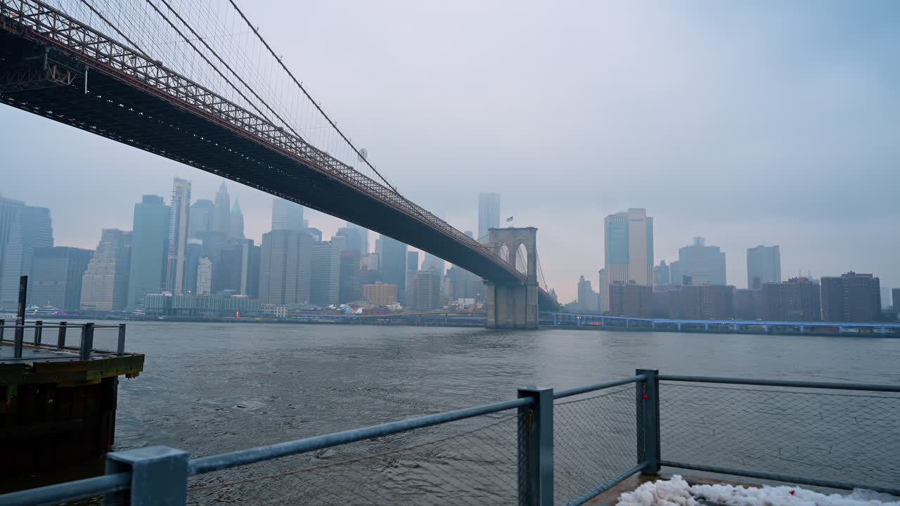 New York, USA, 22. februar 2026: Brooklyn Bridge over East River med Manhattans skyline i tåge. Bredt skud af Brooklyn Bridge med Lower Manhattans skyskrabere indhyllet i dis og vintertåge.