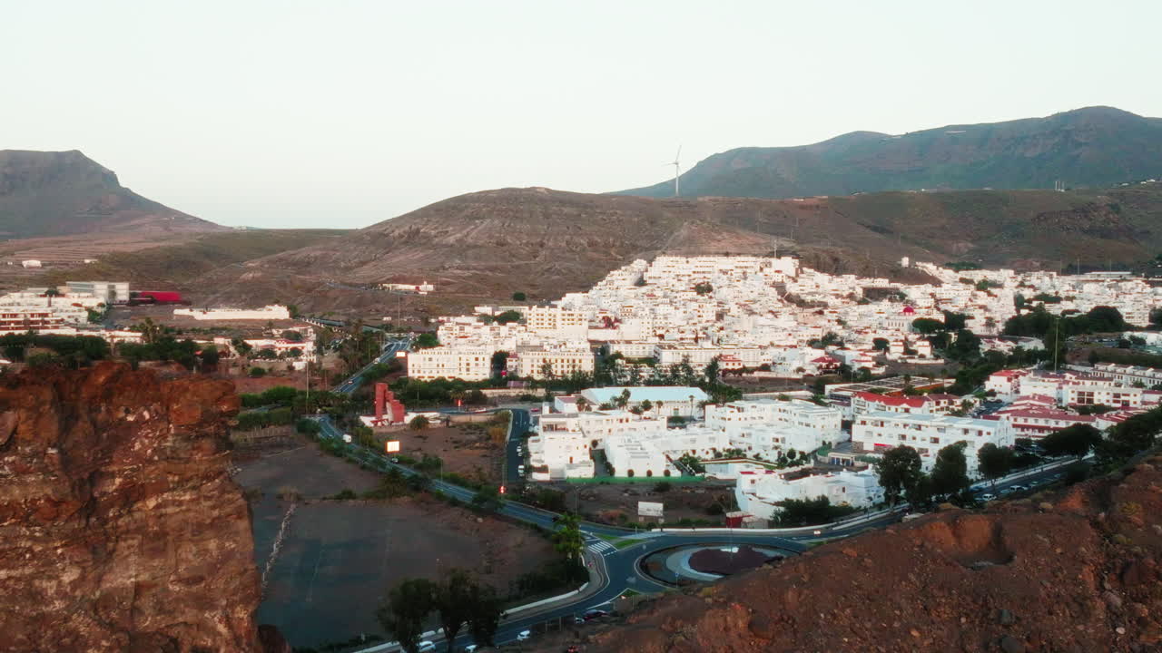 Mountains reveal Gran Canaria housing complex luxury hotel villas, bungalows with wind turbines at back, Canary Island, Aerial view