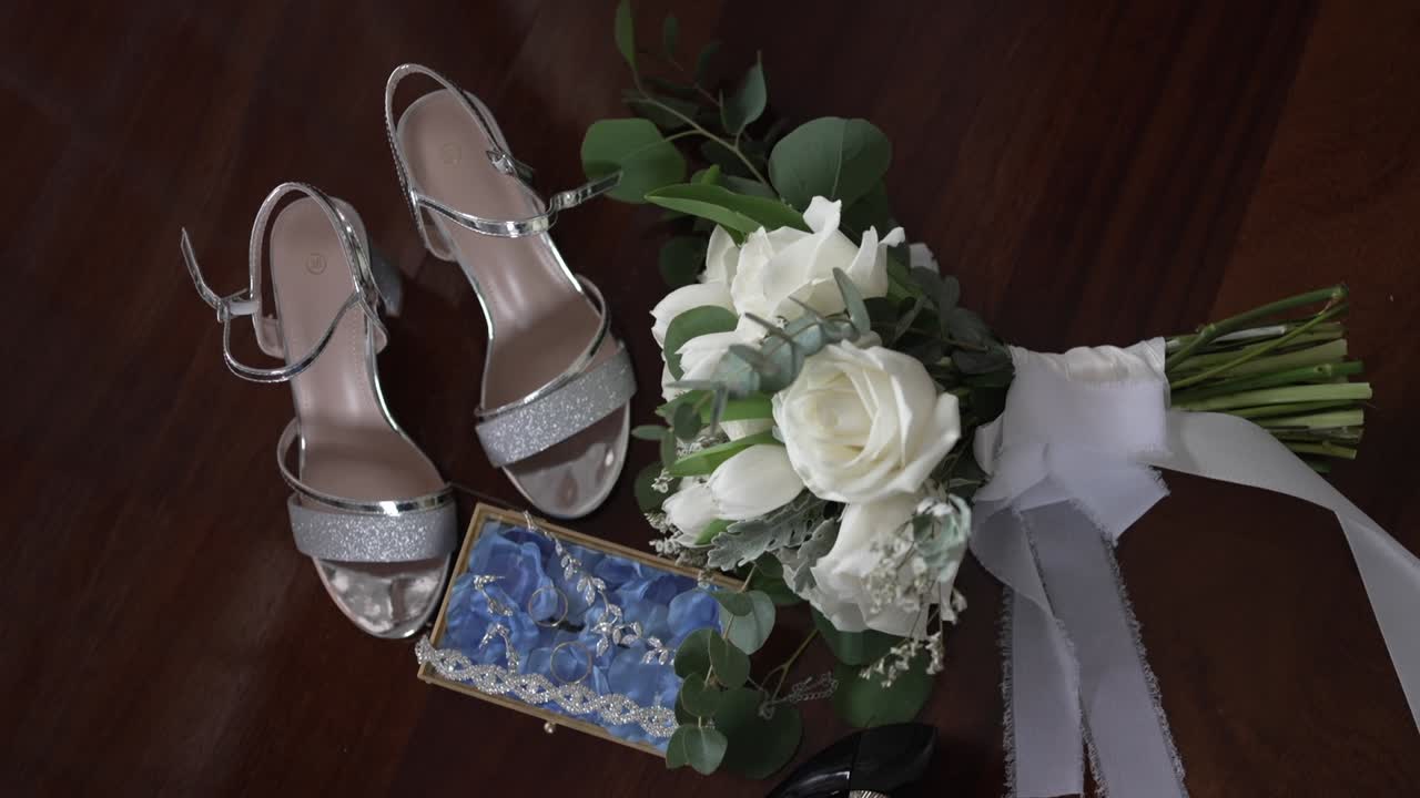 flat lay of bridal heels white rose bouquet and delicate jewelry prepared for wedding day
