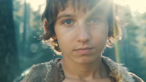 a young boy looks into the camera in a forest