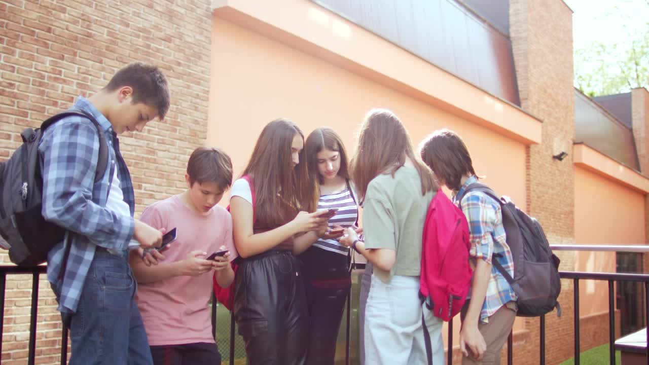 las adolescentes se divierten y conversan usando sus teléfonos móviles