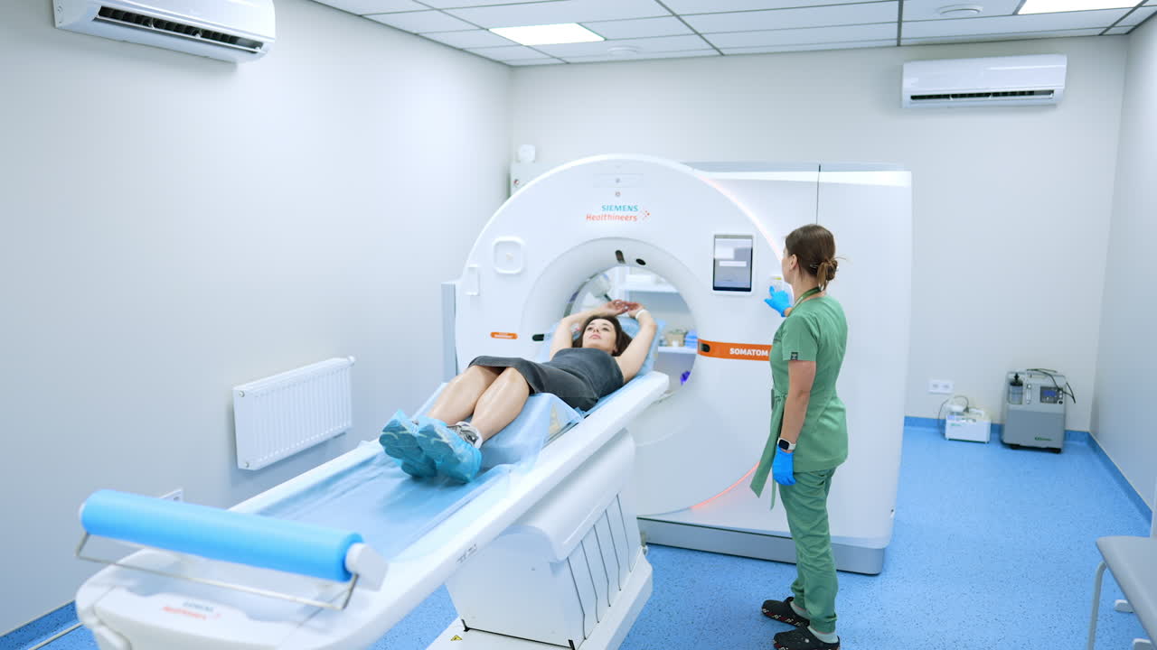 Kyiv, Ukraine, 2 August 2025: Medical worker preparing a patient for a CT scan. Nurse in green scrubs helps a woman lie down on the computed tomography table