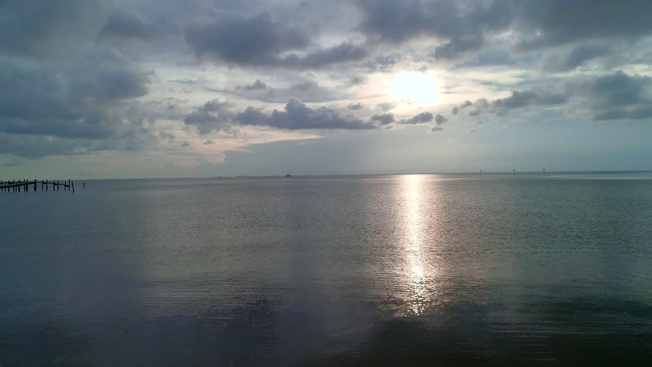 volando sobre una bahía reflectante durante la puesta de sol en un día muy nublado-1