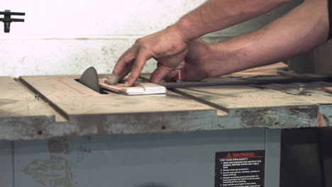 level sliding shot of worker's hands shaping a piece of wood with a table sander