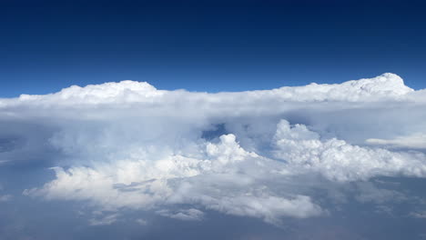 Grandes-Nubes-Blancas-En-Un-Cielo-Azul-Vibrante-Visto-Desde-La-Ventana-Del-Avión