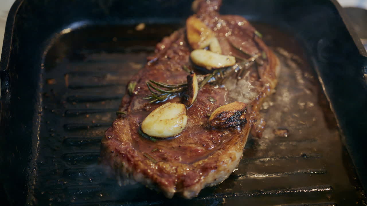 Primo piano di una succulenta bistecca che sfrigola in una padella rovente mentre viene pressata con una spatola