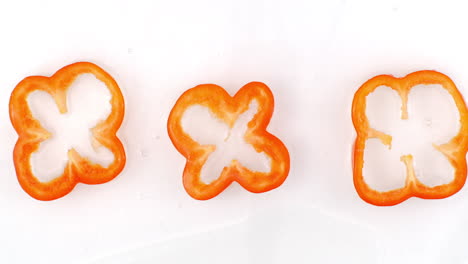 Splashes-of-water-fall-on-sliced-red-pepper-rings-on-a-white-background.-Bulgarian-pepper.