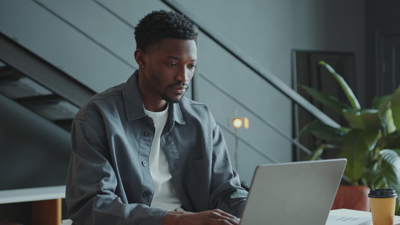 African American Man Working on Laptop at Desk in Office