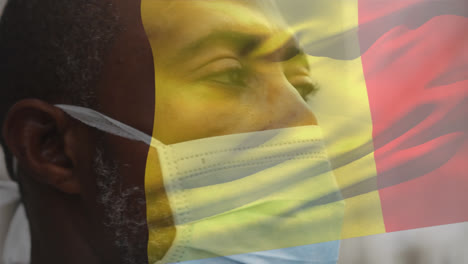Animation-of-flag-of-belgium-waving-over-man-wearing-face-mask-during-covid-19-pandemic