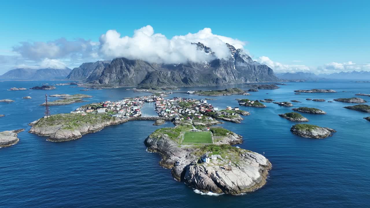 Henningsvaer football field with islands and Lofoten peaks as village and coast come into view