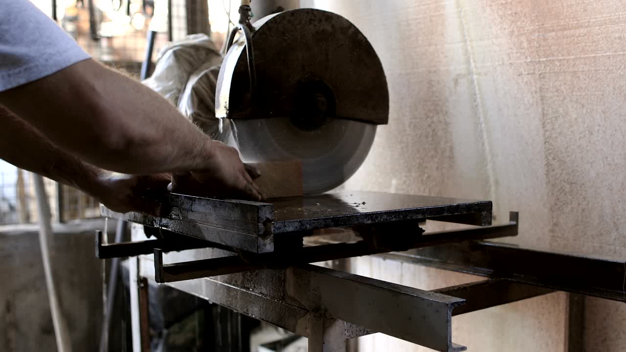 рабочий, разрезающий кирпич циркулярной пилой