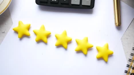 five yellow stars on white paper with office supplies