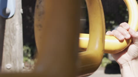 Slow-motion-close-up-of-a-child's-hands-as-she-swings-on-rings-in-a-park-and-lets-go-at-the-end