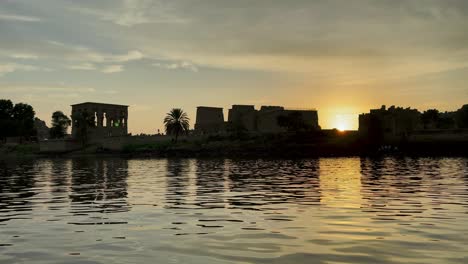 Hermoso-Templo-De-Philae-A-La-Luz-Del-Atardecer-El-Hermoso-Templo-De-Philae-Y-Los-Pilones-Grecorromanos-Se-Ven-Desde-El-Río-Nilo-Un-Templo-Dedicado-A-Isis,-Diosa-Del-Amor-Asuán-Egipcio