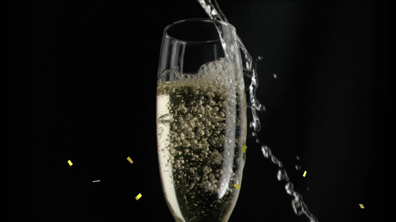 검은색 배경에 페인 유리잔 위에 떨어지는 금색 콘페티의 애니메이션